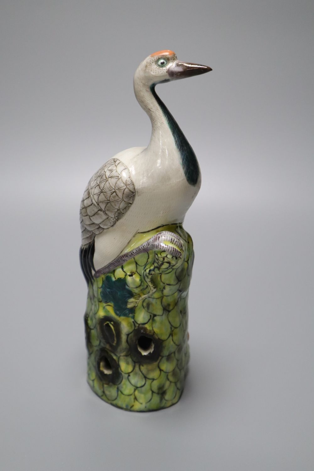 A Chinese enamelled porcelain model of a crane, 19th / 20th century, standing on a pine tree bough, height 24.5cm